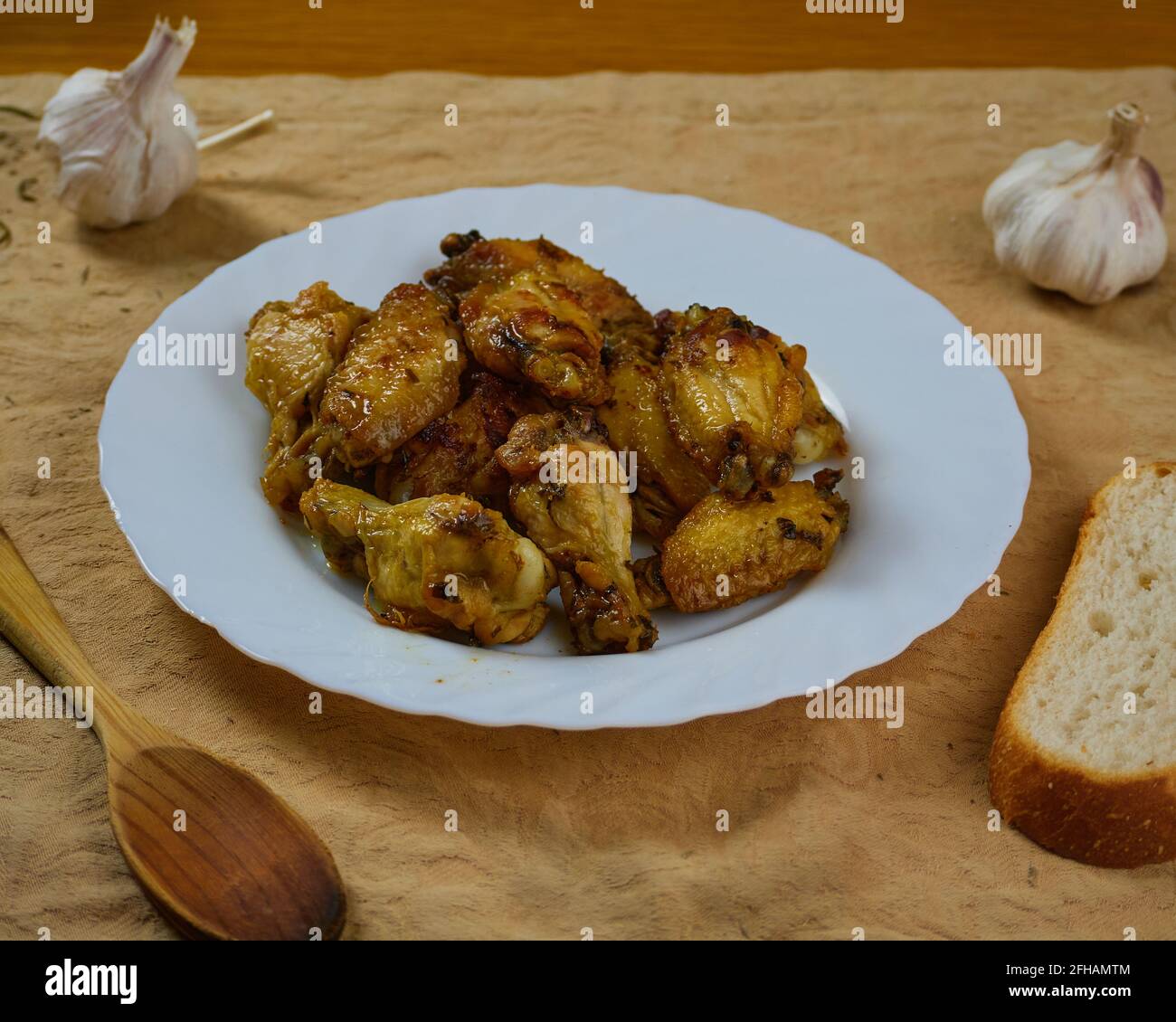 Knoblauch-Hühnerflügel (Pollo al ajillo). Spanisches Tapas-Gericht, serviert mit knusprigem Brot und seinen Zutaten auf einer braunen Serviette. Stockfoto