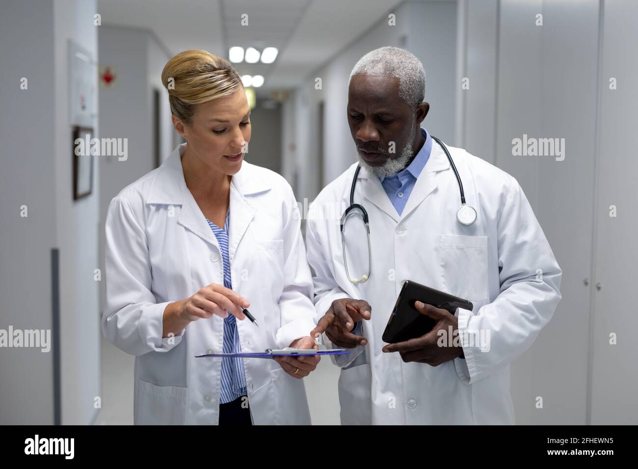 Verschiedene Ärzte stehen im Krankenhausflur und schauen nach In der medizinischen Dokumentation Stockfoto