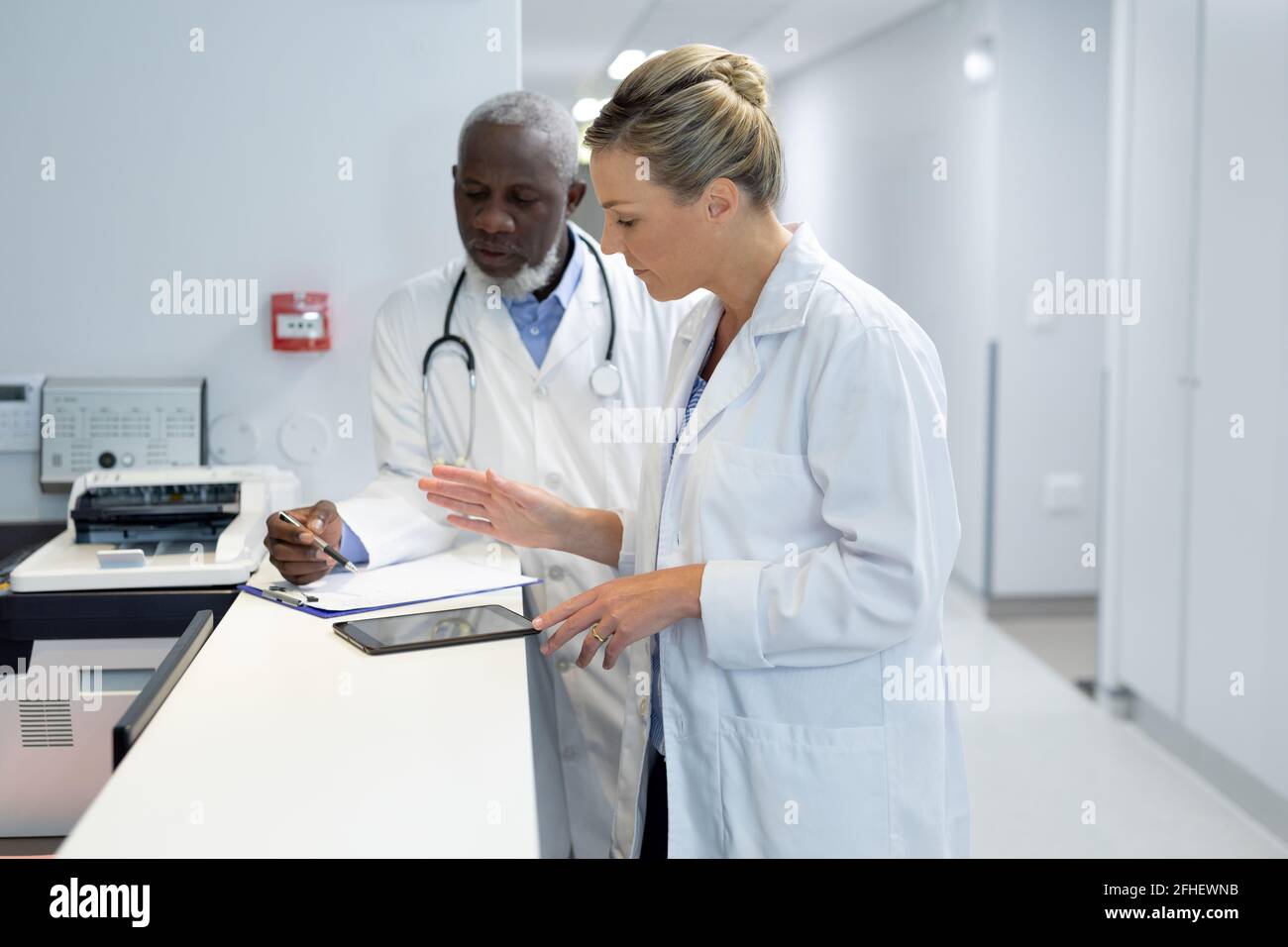 Verschiedene Ärzte stehen im Krankenhausflur und schauen nach In der medizinischen Dokumentation Stockfoto
