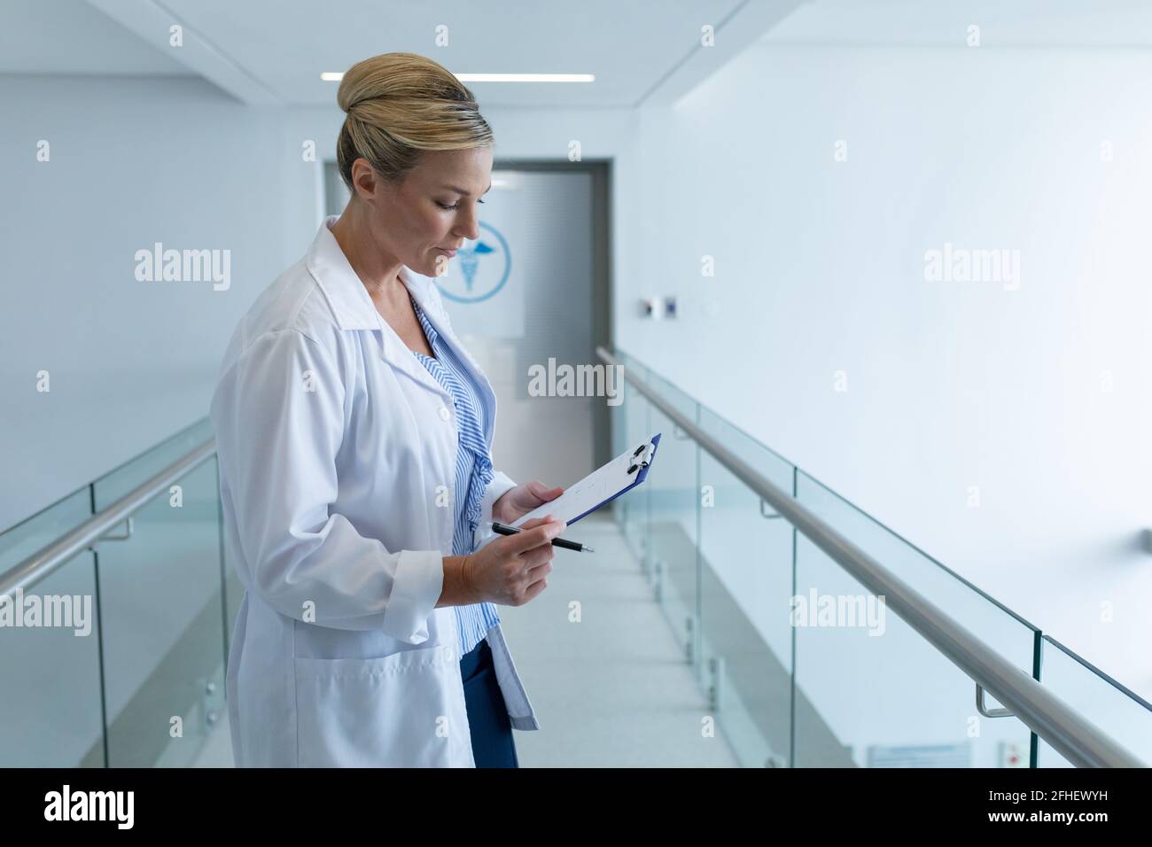 Kaukasische Ärztin, die im Krankenhauskorridor steht und sich einen Arzt ansieht Diagrammdokument Stockfoto