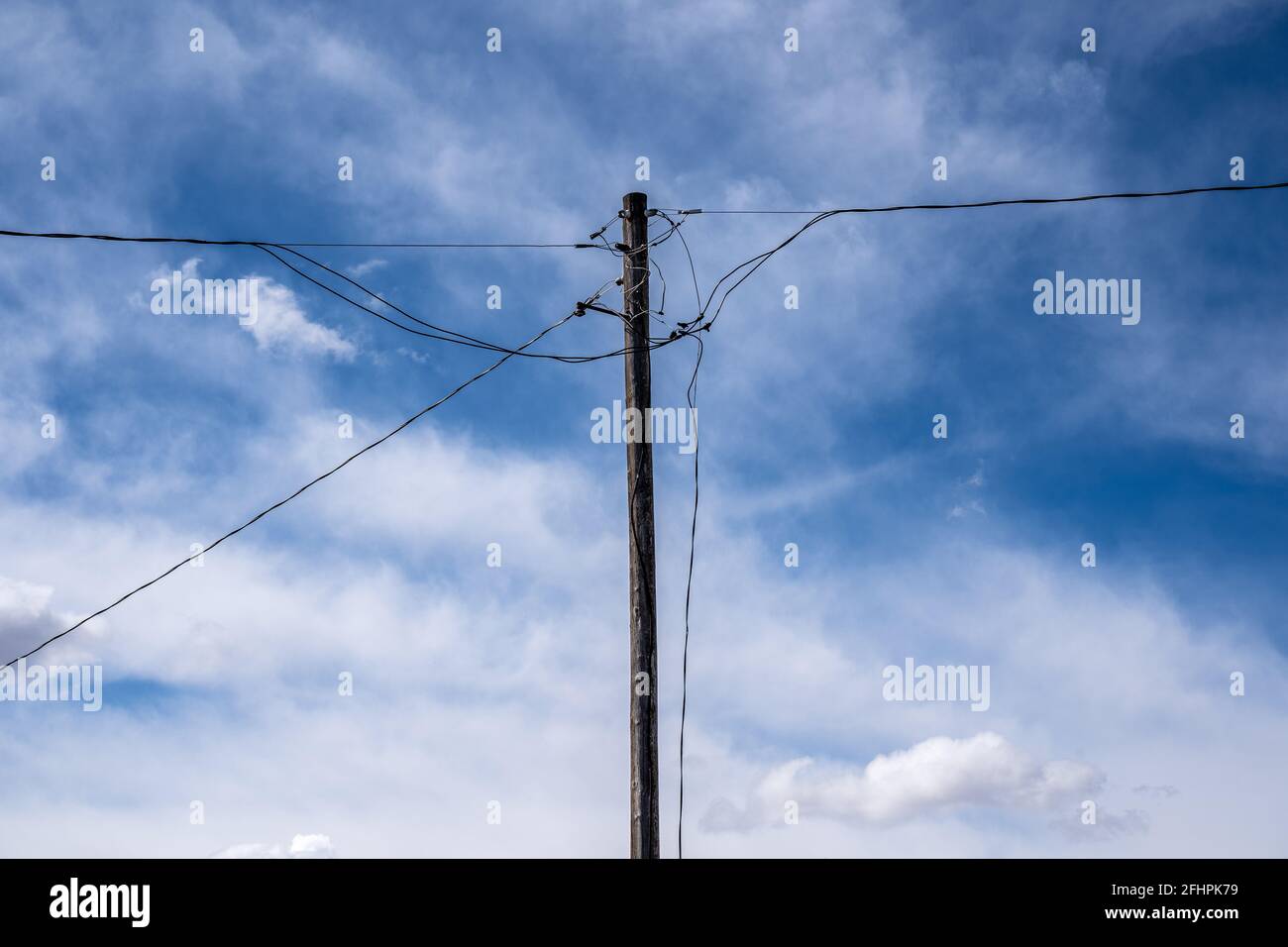 Ein alter Strommast mit Stromleitungen und Kommunikationsleitungen auf einem ländlichen Grundstück in Rocky View County Alberta, Kanada. Stockfoto