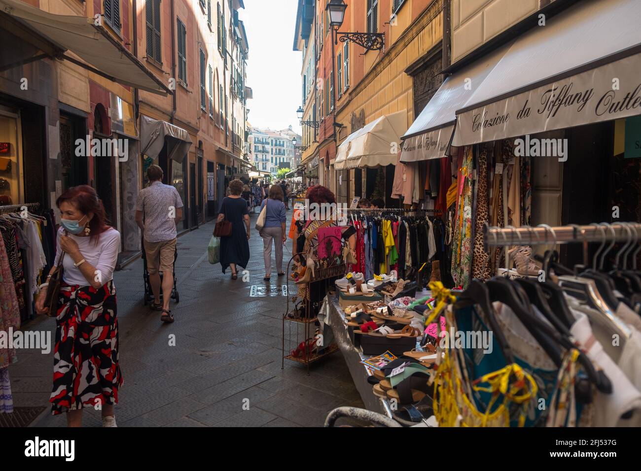 In einer engen Einkaufsstraße in der Fußgängerzone der Altstadt von Rapallo stehen Kleidungsstücke zum Verkauf. Stockfoto