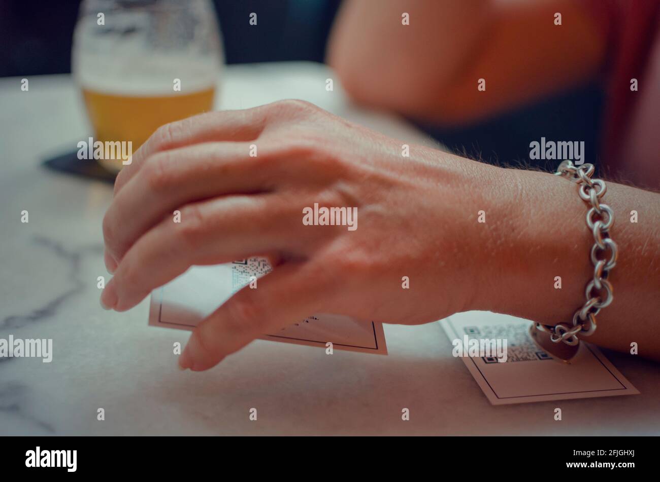 Hand einer kaukasischen Frau mit einem QR-Code-Menü in einem Restaurant. Selektiver Fokus auf die Karte. Stockfoto