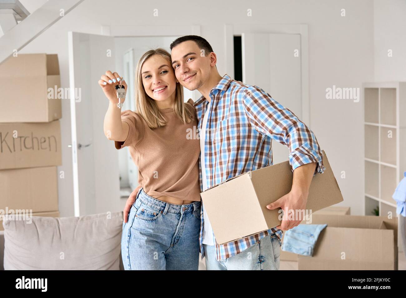 Glückliches junges Paar zum ersten Mal Hausbesitzer mit Schlüsseln in neuem Haus. Stockfoto