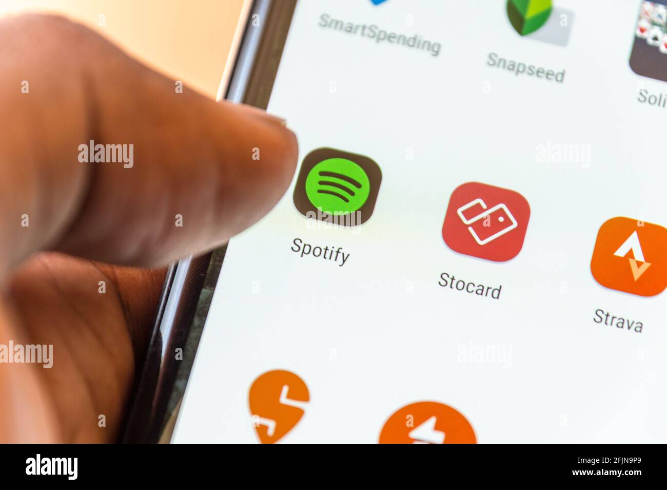 Erwachsene Männer, die das Smartphone bedienen und die Spotify-App auf dem auswählen Angezeigt Stockfoto