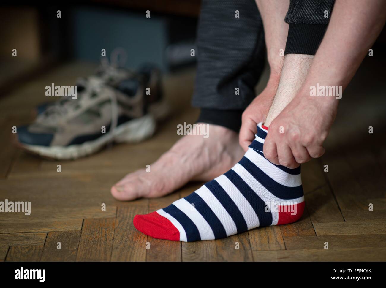 Der Mann setzt bunt gestreifte Socken und Schuhe gezeigt Im Hintergrund Stockfoto