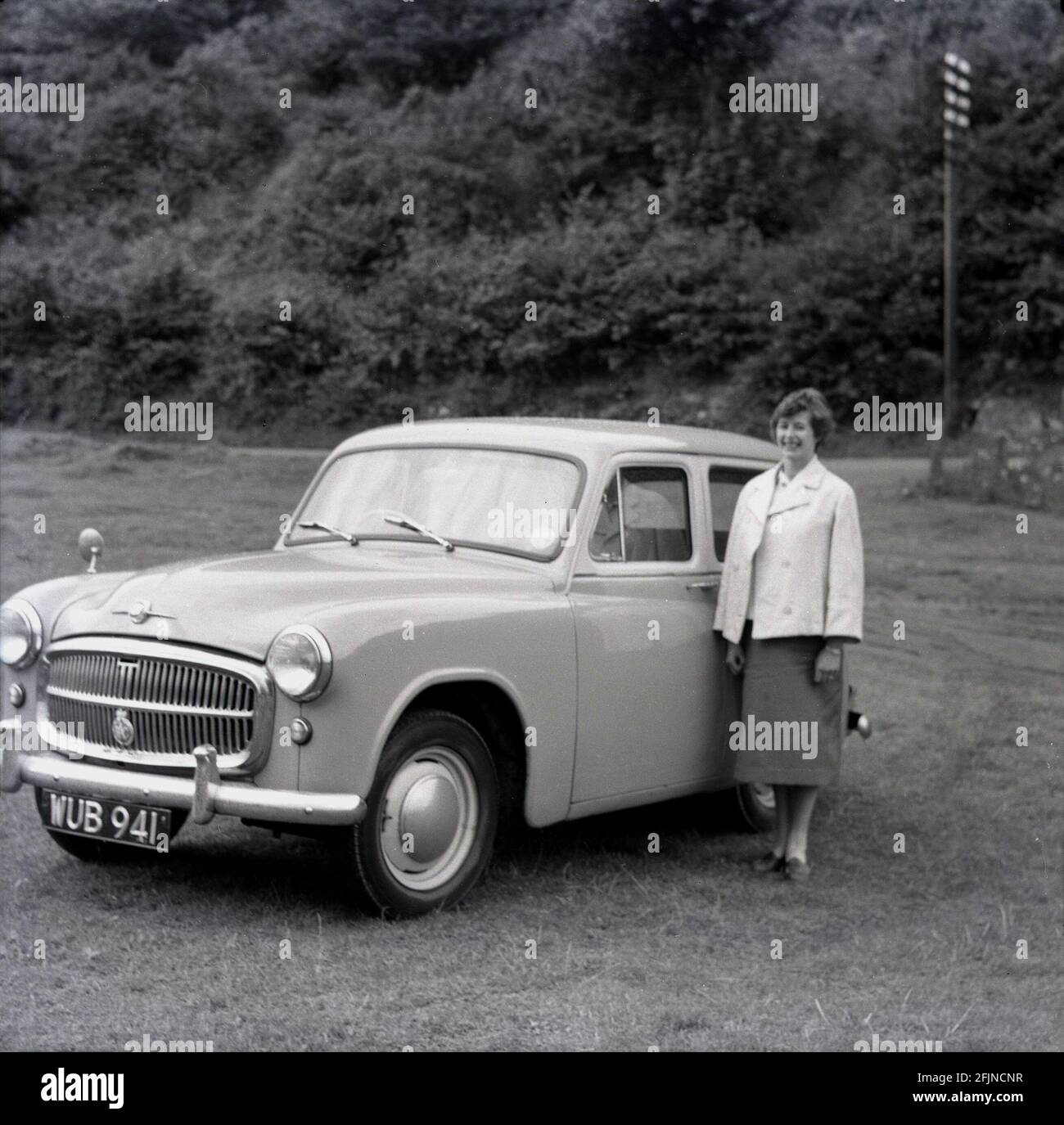 1958, historisch, eine Dame, die bei ihrem Auto aus der Zeit stand, parkte auf einem Wiese auf einem Autourlaub in Schottland, Großbritannien. Stockfoto