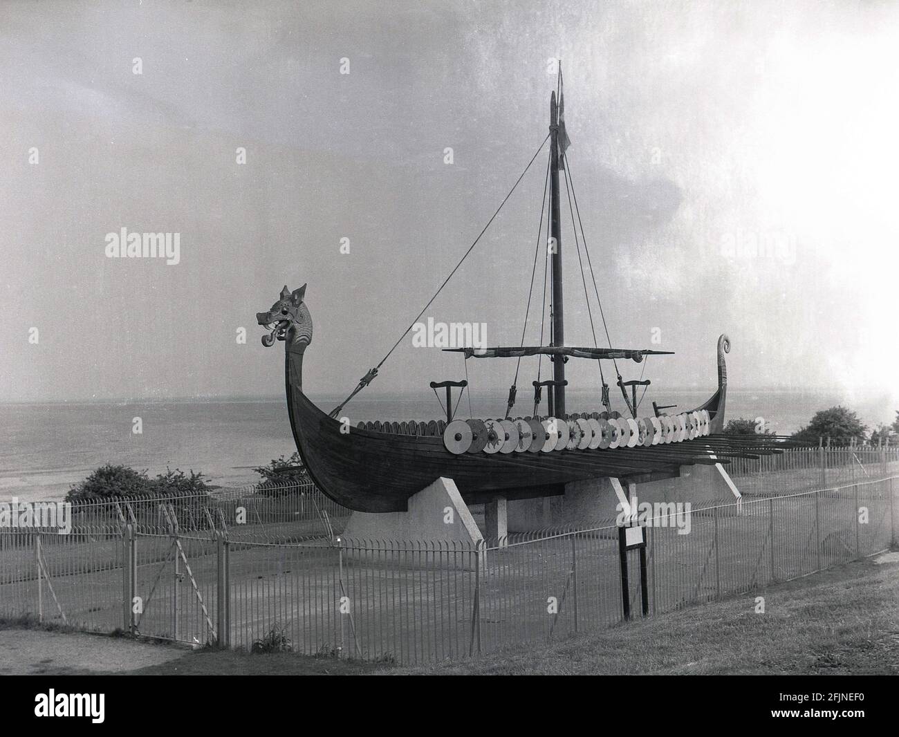 1958, das Wikingerschiff oder Langboot "Hugin", das an der Küste auf der Pegwell Bay Klippe, Ramsgate, Kent, England, Großbritannien, ausgestellt wird. Ein rekonstruiertes Langschiff, die Hugin, ein Geschenk des dänischen Schenkers zum Gedenken an den 1500. Jahrestag von Hengist und Horsa, Anführer der angelsächsischen Invasion in der nahegelegenen Ebbsfleet, kam 1949 in Viking Bay, Broadstairs an. Es ist eine Nachbildung des Gokstad-Schiffes, ca. 890. Stockfoto