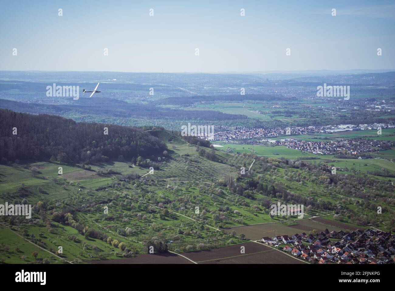 Der Segelflieger schwebt über ein Tal in Deutschland, in der Nähe von Stuttgart. Blick von einer Klippe zeigt die ländlichen Dörfer, viele Felder und Bäume in einem besiedelten Gebiet. Stockfoto