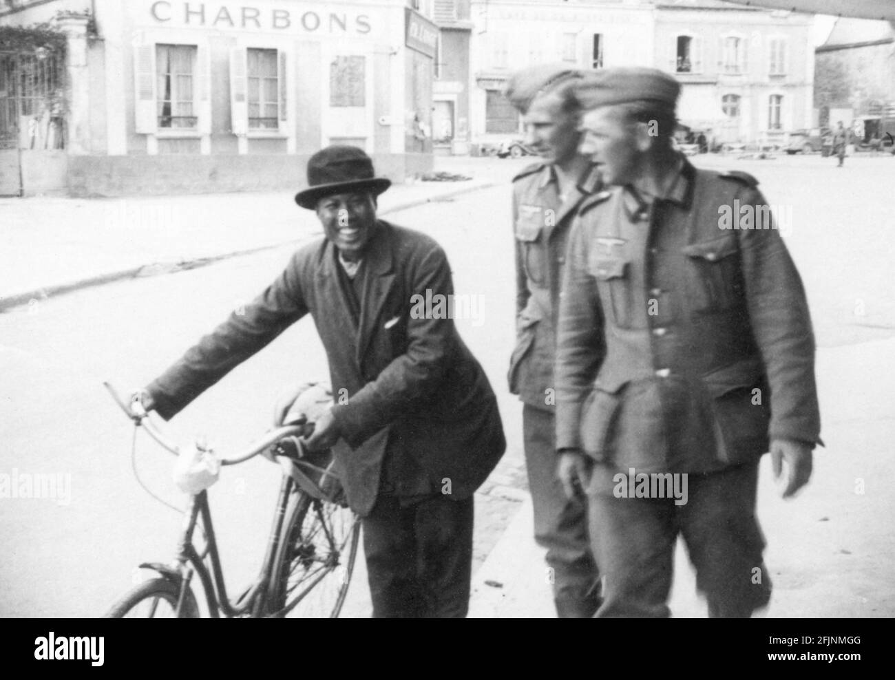 deutsche Soldaten im Gespräch mit einem Schwarzafrikaner mit Fahrrad (Abbeville Oktober 1940) Stockfoto