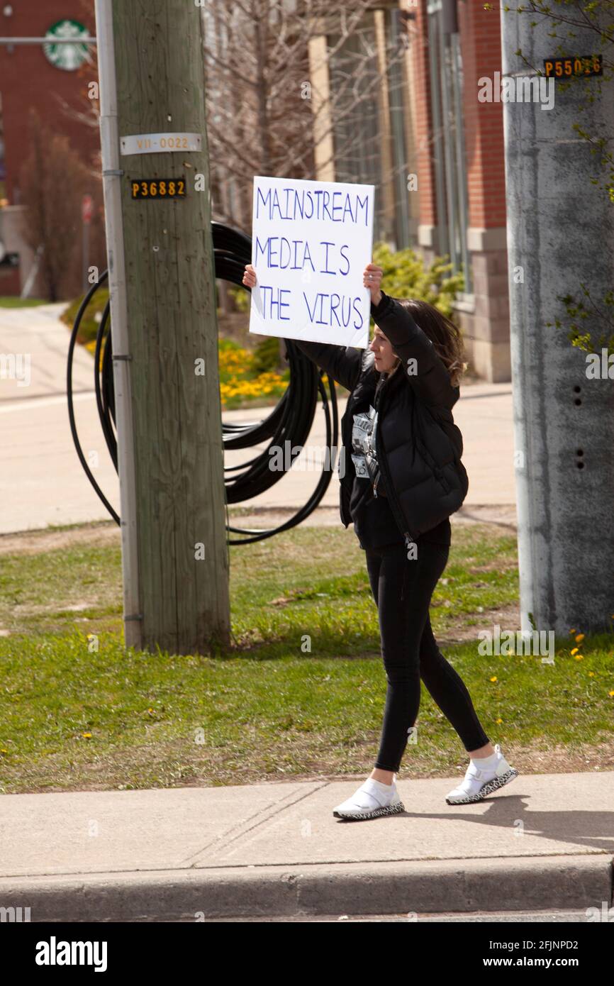 Vaughan, Kanada – 25. April 2021: Frau mit Mainstream-Medien ist das Virus-Zeichen aus Protest gegen COVID-19-Stillstandsmaßnahmen in Ontario Stockfoto