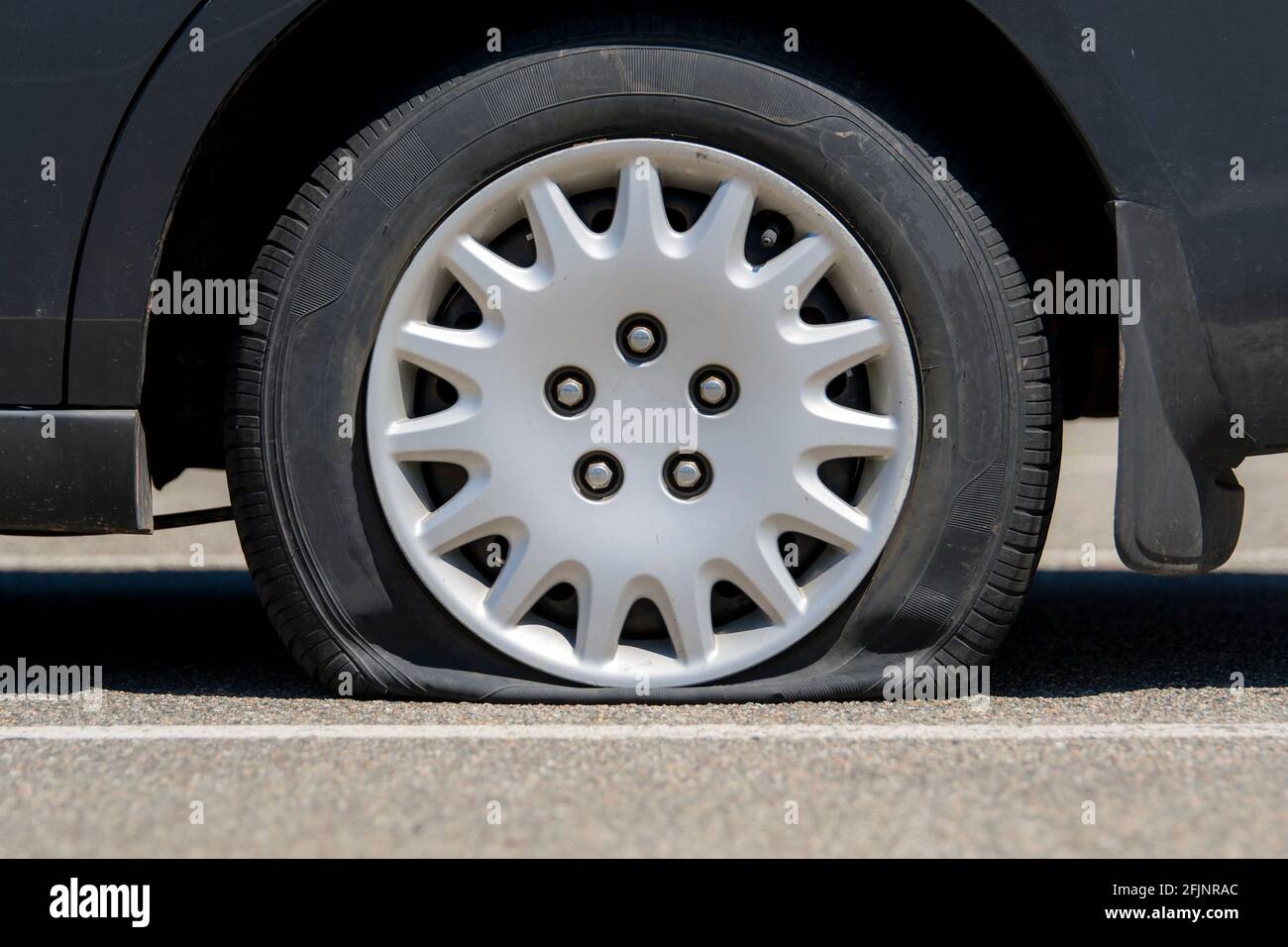 Reifenpanne auf einem schwarzen Auto. Nahaufnahme mit niedrigem Winkel. Stockfoto