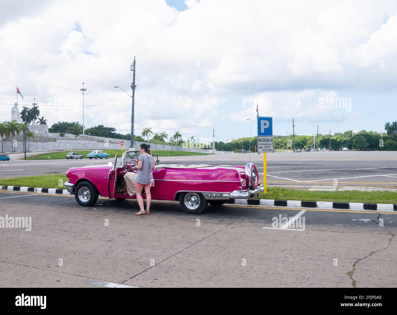 Touristen sitzen auf der Rückseite eines farbenfrohen Cabriolets aus den 1950er Jahren am Platz der Revolution in Havanna, Kuba Stockfoto