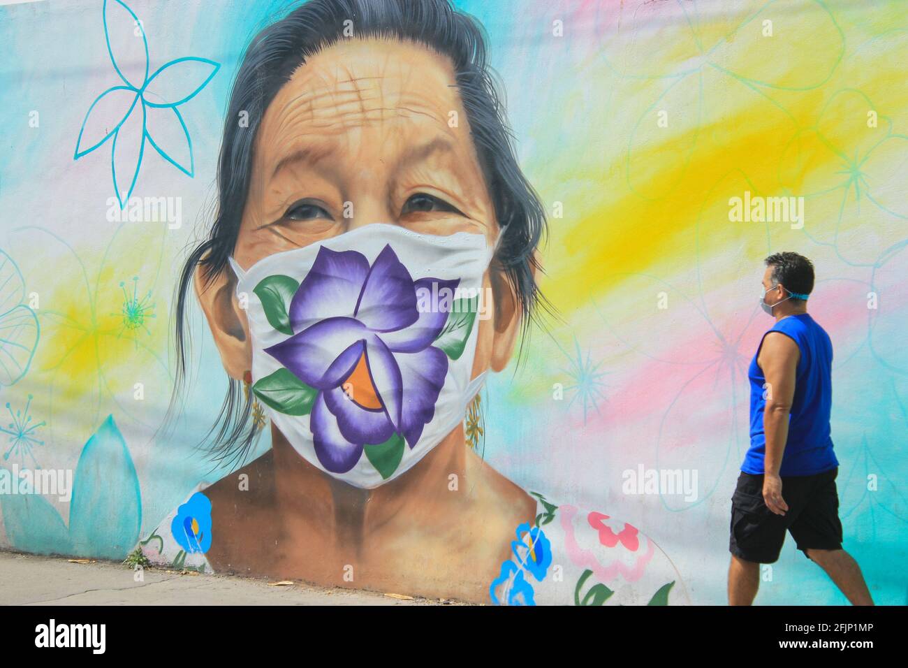 Mexikanischer Mann, der vor einem Wandgemälde eine Maya-Frau mit Gesichtsmaske zeigt, Covid-19 Pandemie, 2021. April, Merida Mexiko Stockfoto