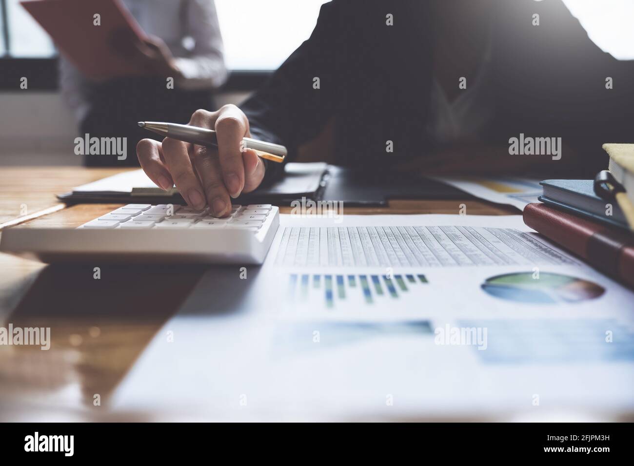 Das Projektmanagement-Team aktualisiert und berechnet das Finanzdiagramm auf Papierdokumenten, zwei Geschäftsleute im Büro. Stockfoto