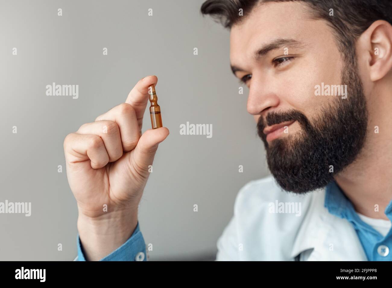Lächelnder Arzt Wissenschaftler beim Betrachte der Ampulle des Impfstoffes aus der Nähe Porträt Stockfoto