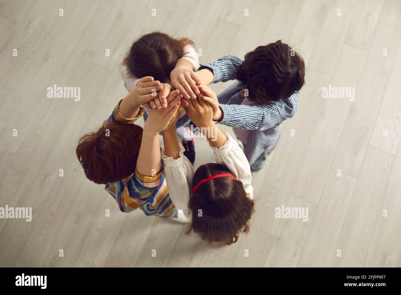 Blick von oben auf ein Team von kleinen Kindern, die in der Nähe stehen Im Kreis und mit Händen Stockfoto