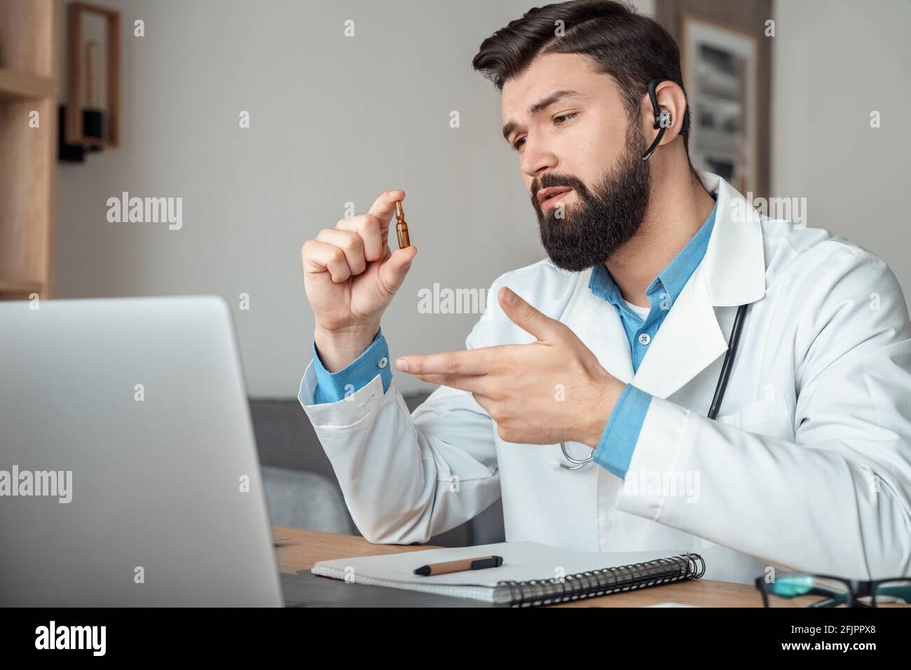 Arzt mit Grippe-Coronavirus-Impfampulle geben Online-Präsentation auf Notebook Stockfoto