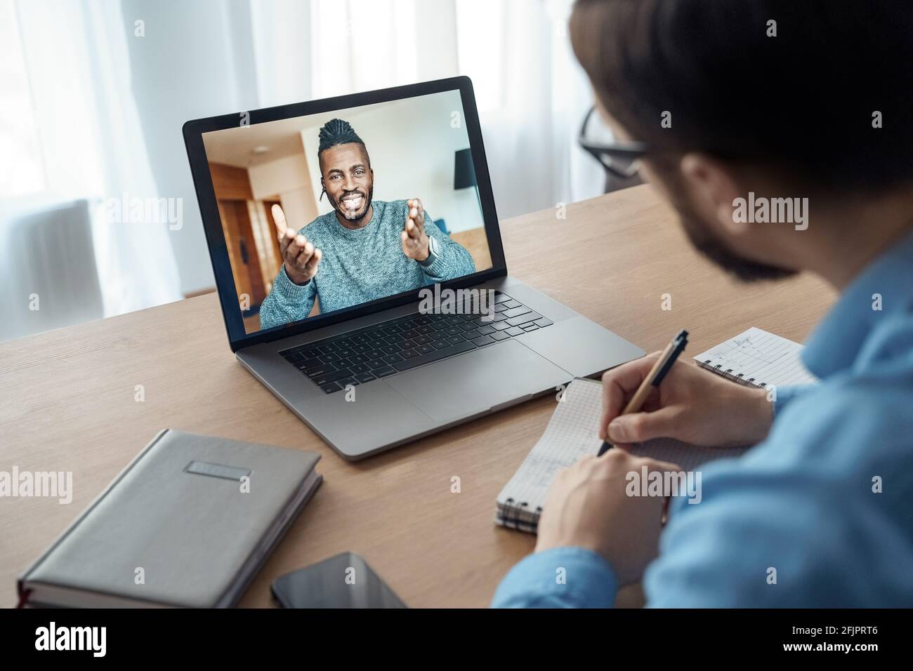 Rückansicht eines Millennial-Mannes, der sich Online-Schulungen oder -Kurse ansieht Auf einem Laptop Stockfoto