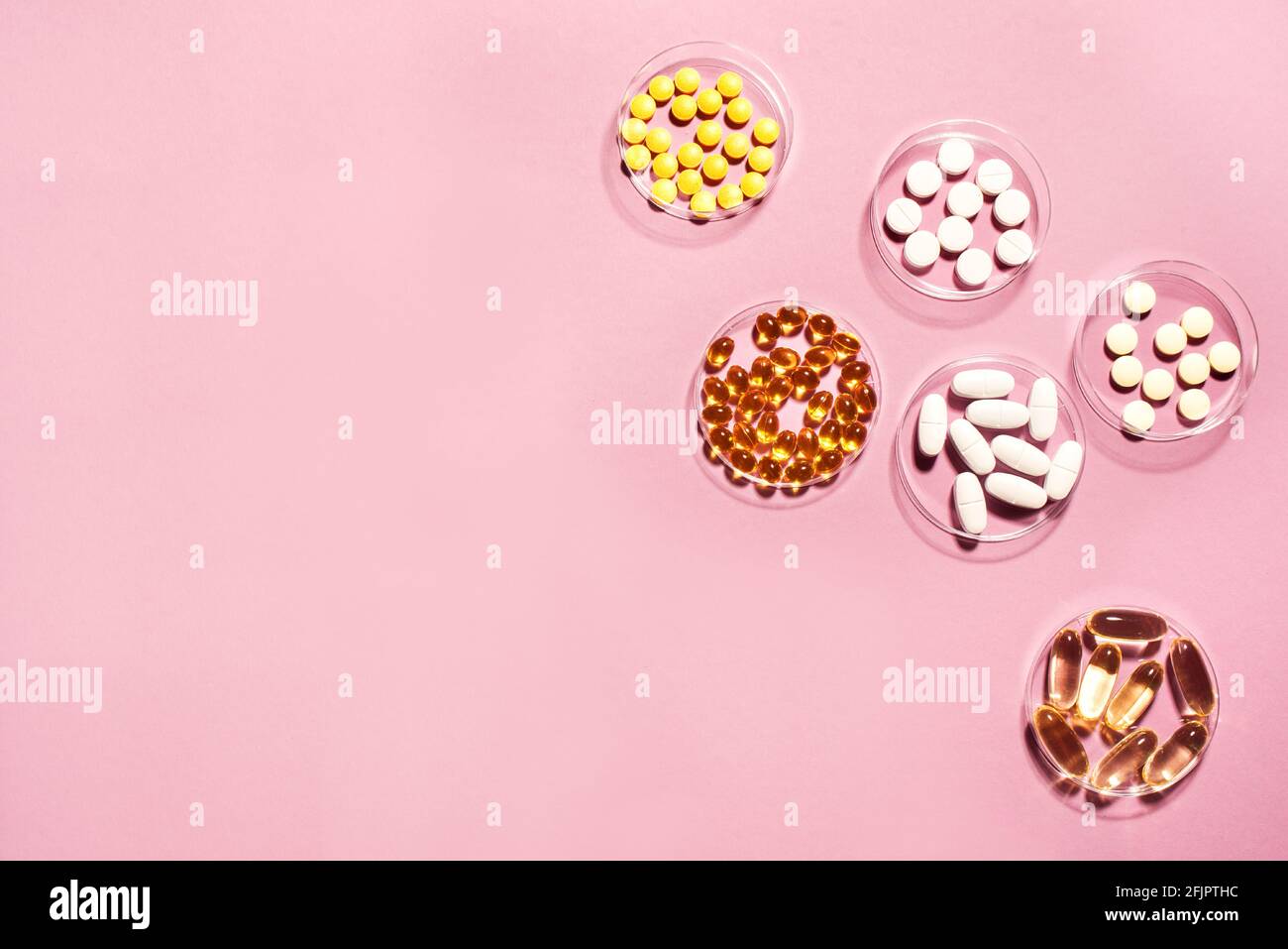 Vitamine Kapseln auf rosa Hintergrund, Draufsicht, Kopierraum. Nahrungsergänzungsmittel: Fischöl, Omega 3, Omega 6, Omega 9, Vitamin A, D3, E, B, KALZIUM. Stockfoto