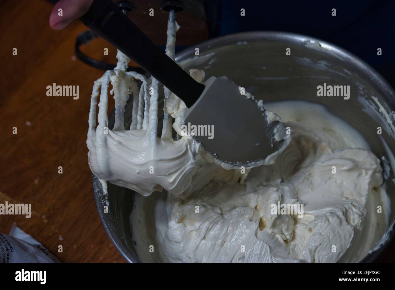 Frau, die einen Teig mit einem Spatel zusammenfaltet Stockfoto