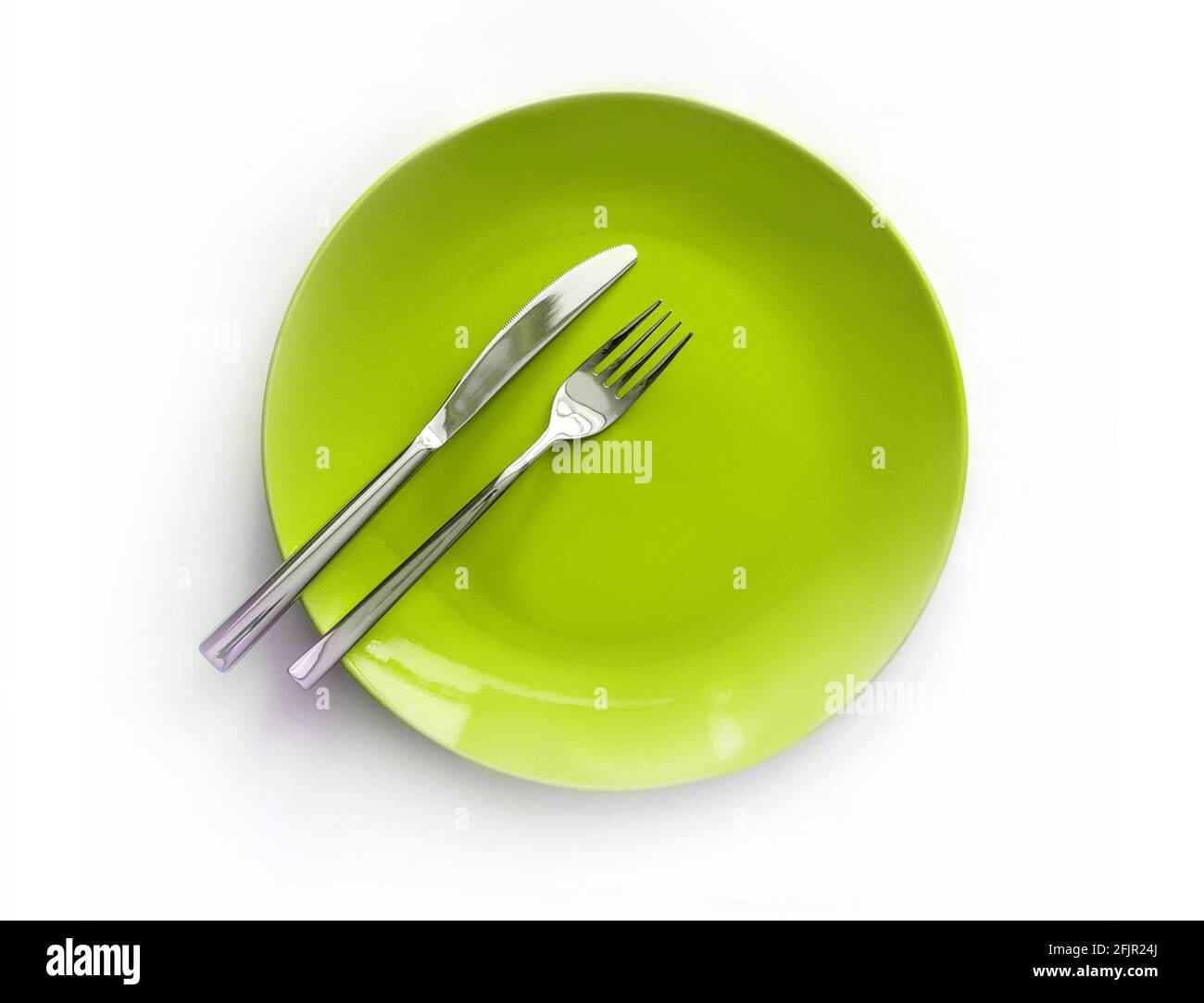 Servierte Teller mit Besteck. Leere grüne Platte und Edelstahlmesser und Gabel isoliert auf weißem Hintergrund. Draufsicht Stockfoto