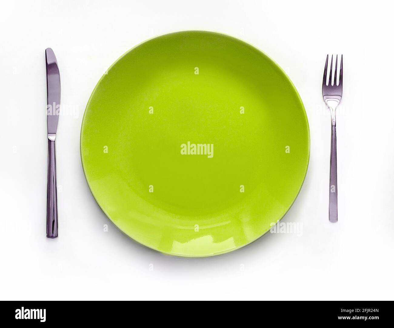 Servierte Teller mit Besteck. Leere grüne Platte und Edelstahlmesser und Gabel isoliert auf weißem Hintergrund. Draufsicht Stockfoto