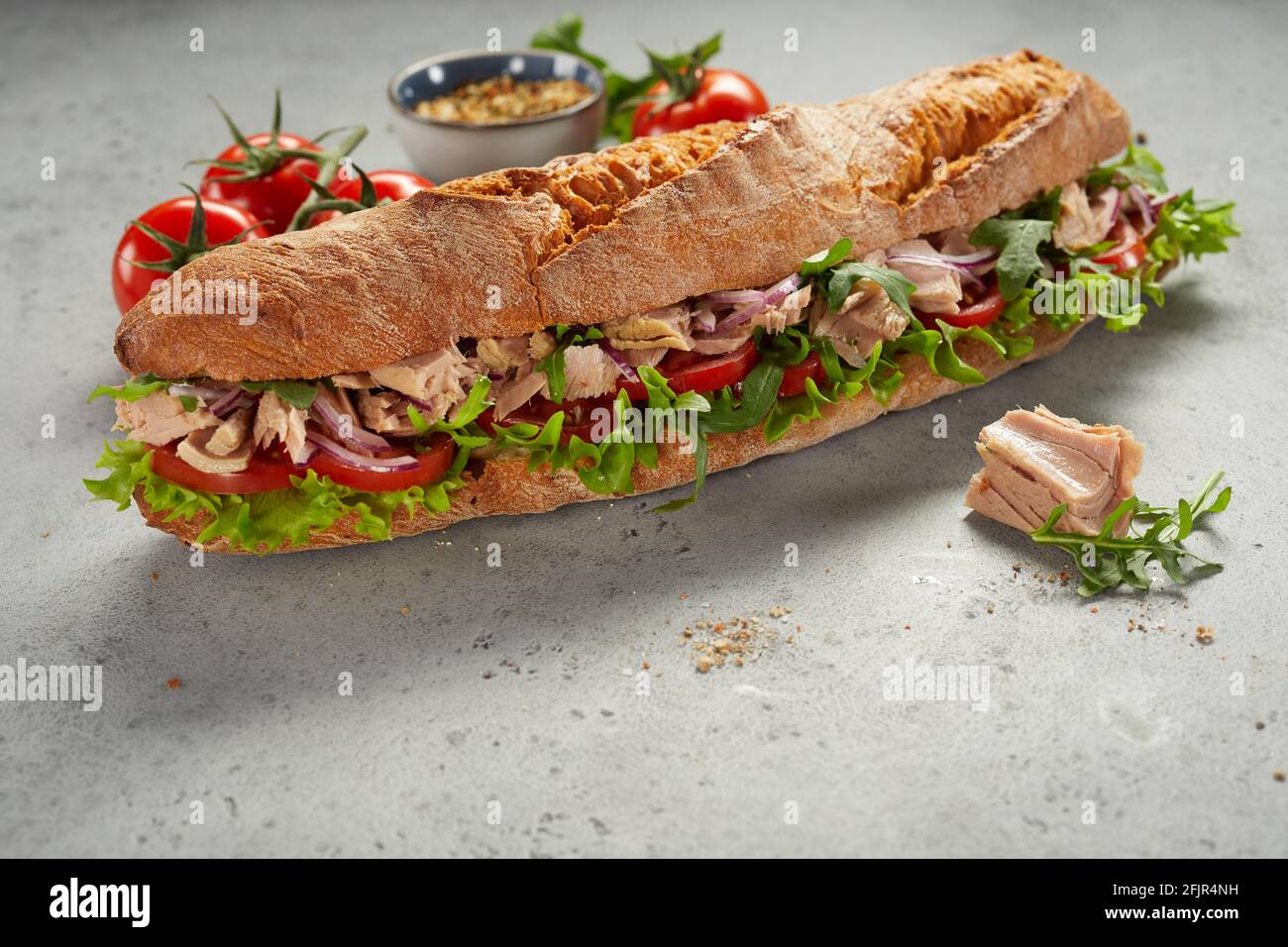 Leckere frische Sub-Sandwich mit Fleisch und verschiedenen Gemüse platziert  Fast reife Tomaten und Gewürze auf grauem Tisch Stockfotografie - Alamy