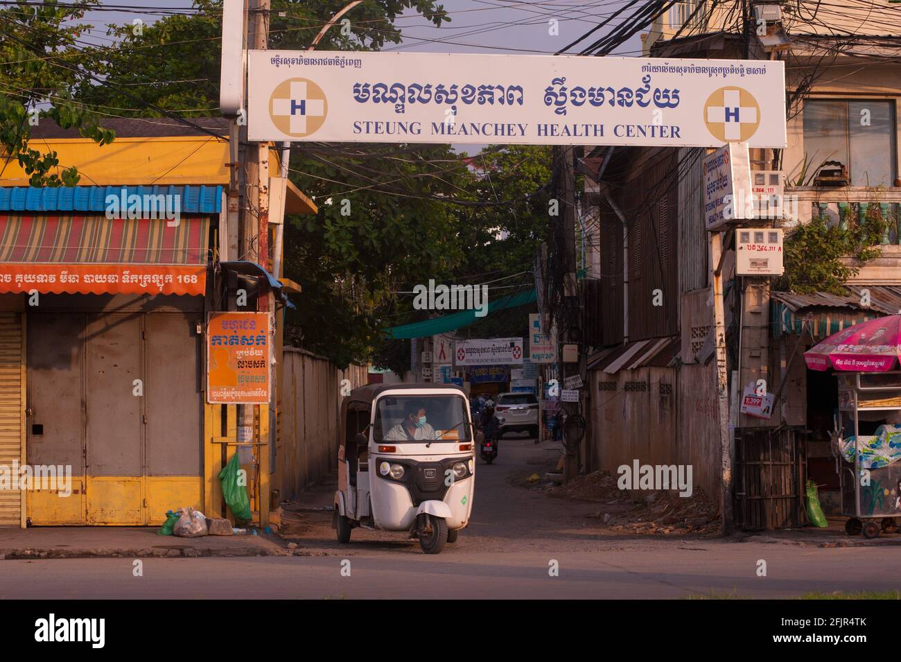 Aufgrund eines kürzlichen Ausbruchs von COVID - 19 in einer Bekleidungsfabrik hat die kambodschanische Regierung eine Sperre auferlegt, hier zieht während der Coronavirus-Pandemie ein indischer Tuk-Tuk aus dem Steung Meanchey Health Center auf eine leere Straße. Stueng Meanchey, Phnom Penh, Kambodscha. April 2021. © Kraig Lieb Stockfoto