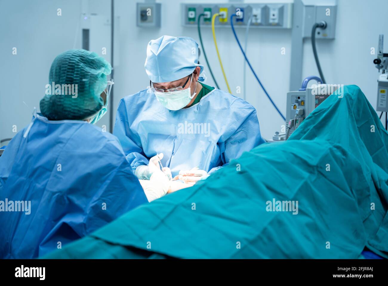 Chirurgen und ein Assistent geben Instrumente aus, die den Knochen im Arm des Patienten im Operationssaal operieren. Professionelle Ärzte Durchführen Stockfoto