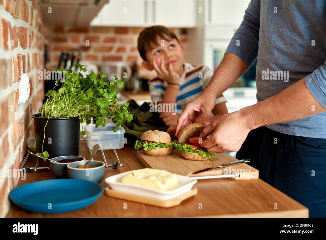 Nahaufnahme des Vaters, der in der Küche ein Mittagessen für den Sohn zubereitet Stockfoto