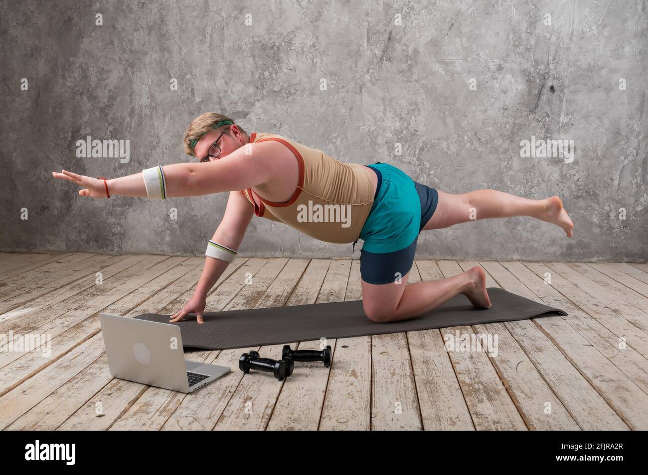 Lustige fette Mann in Sportbekleidung tun Sport-Übungen Blick in einen Laptop. Home Workout Stockfoto
