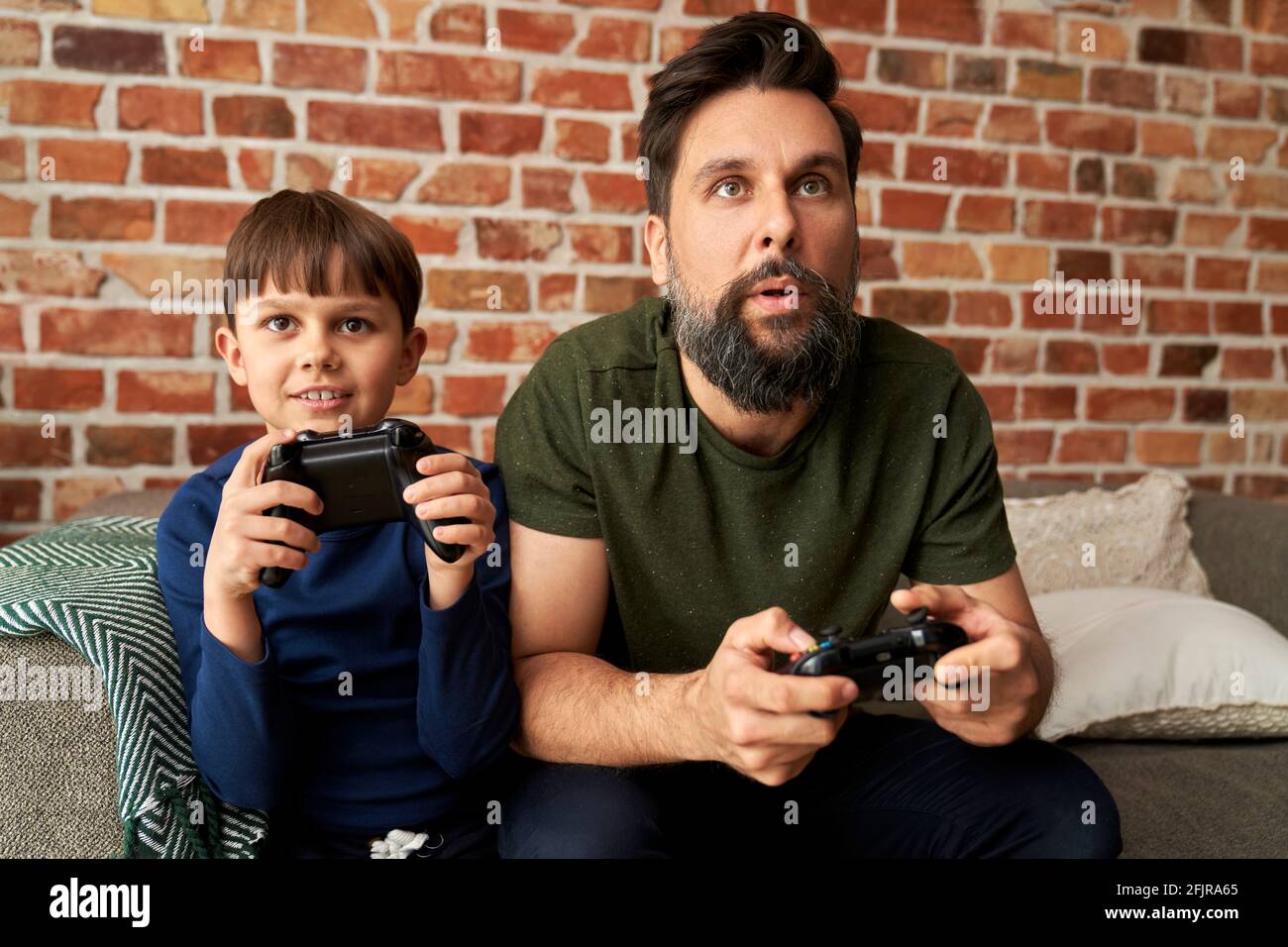 Fokussierter Vater und Sohn spielen Videospiel zusammen Stockfoto