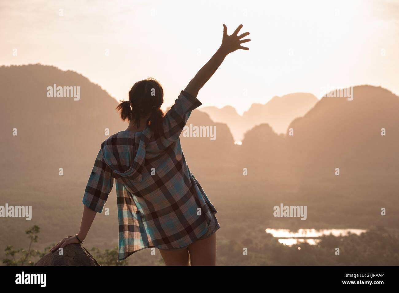 Glückliches schlankes Hipster-Mädchen steht am Aussichtspunkt gegen Meer und Inseln bei Sonnenaufgang. Phang Nga Bay, Thailand Stockfoto
