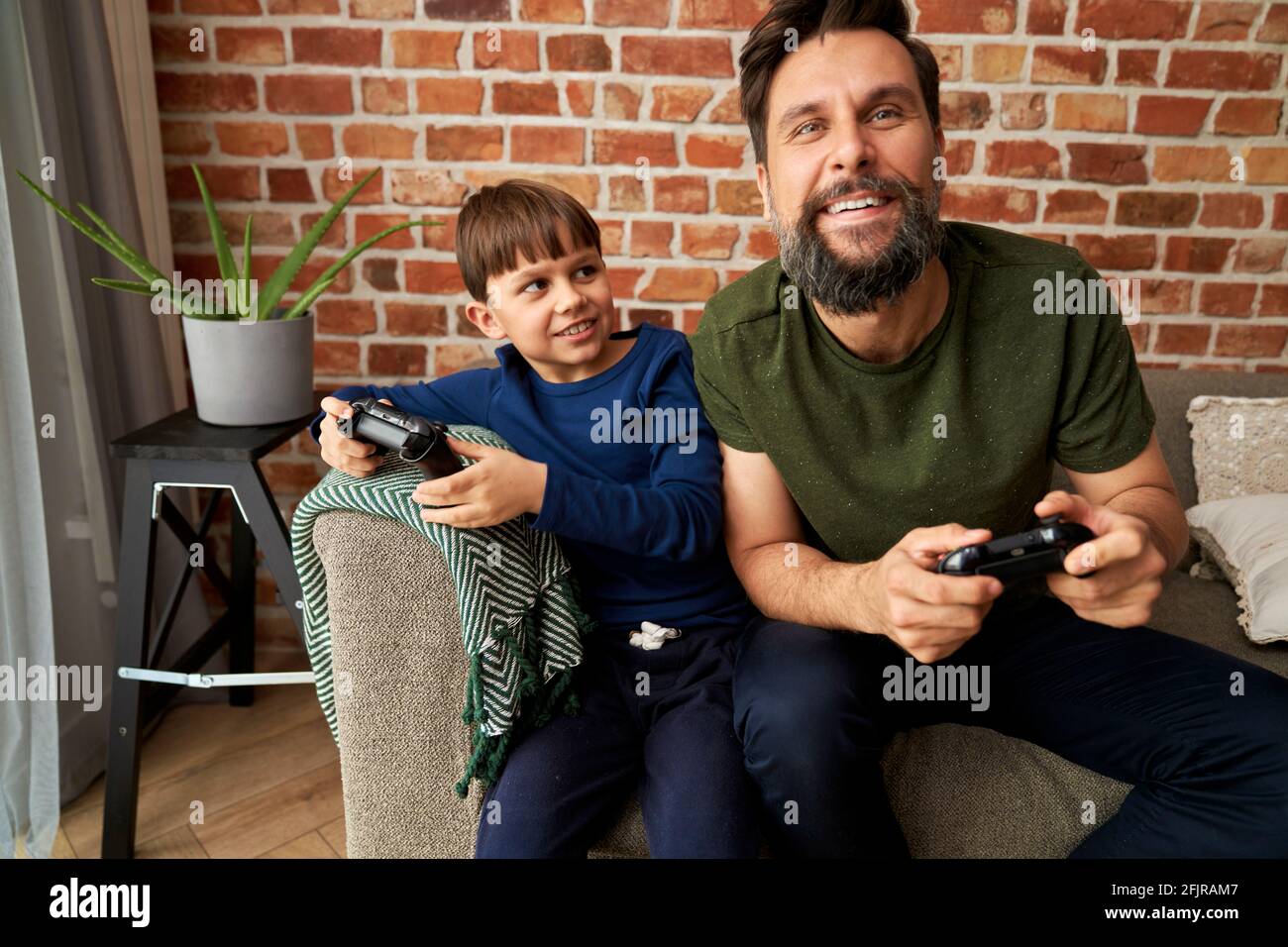 Vater, der mit seinem Sohn Spaß am Spielen von Videospielen hat Stockfoto