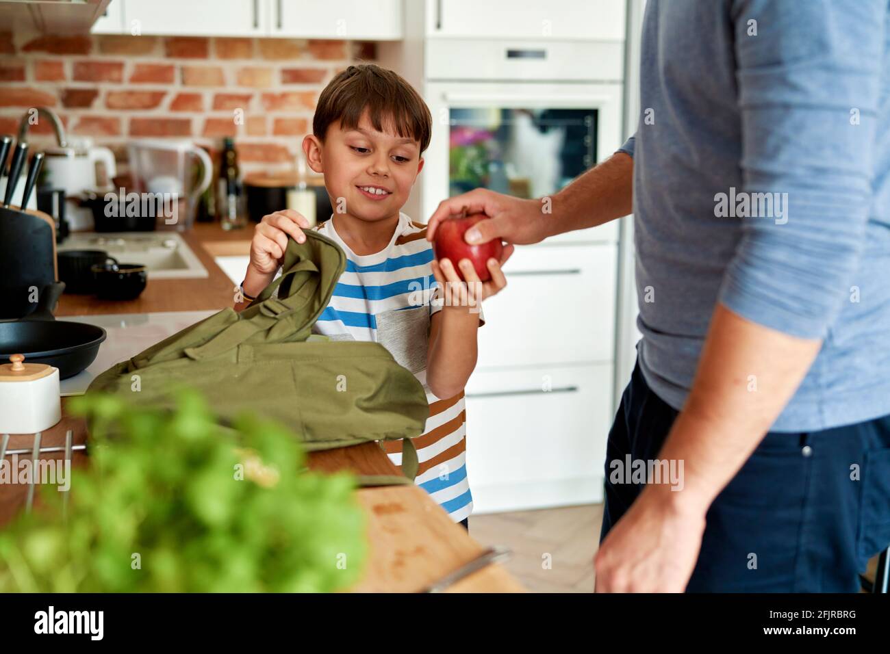 Junge mit Vater, der gesunde Nahrung für die Schule verpackt Stockfoto