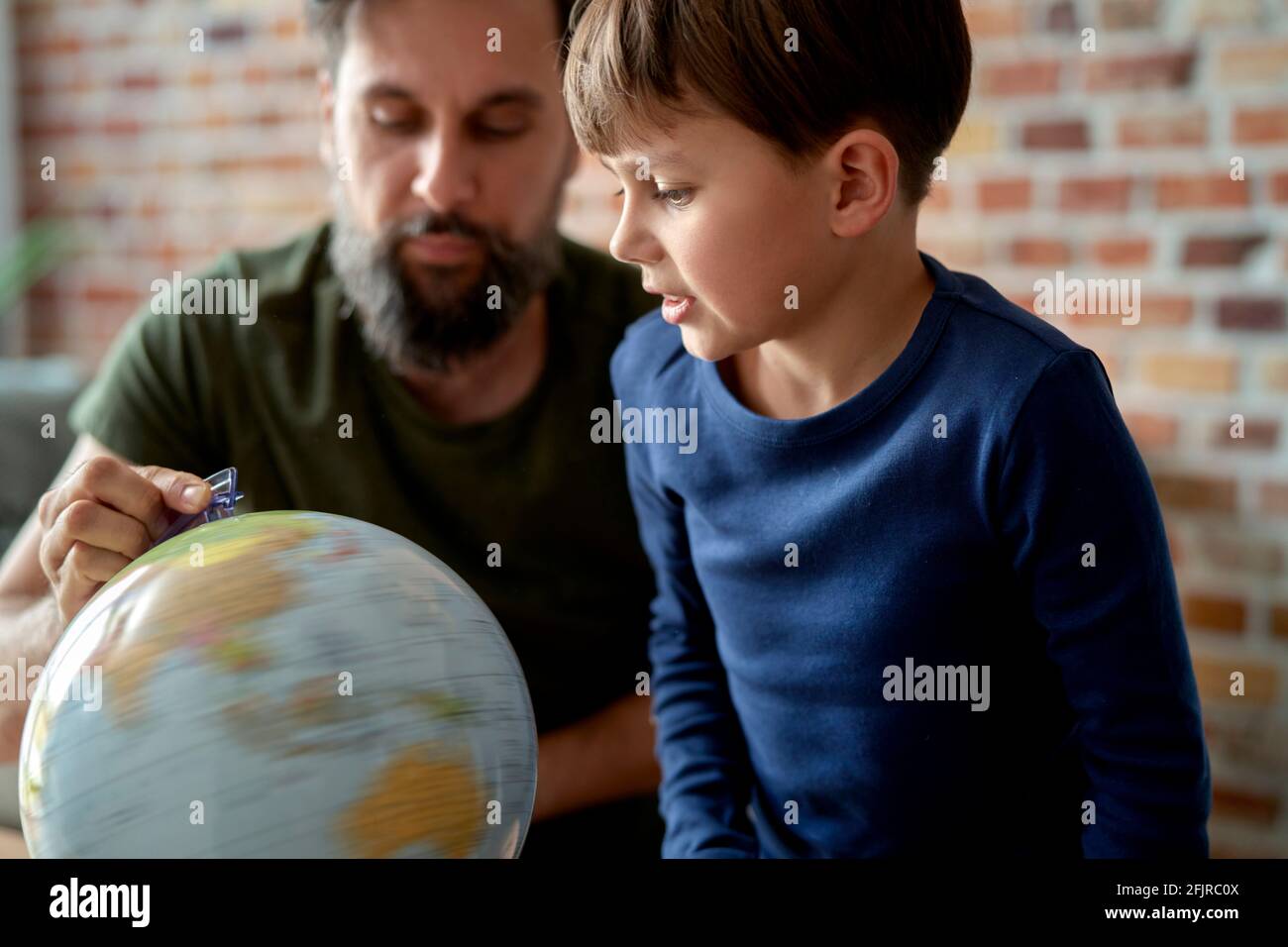 Sohn und Vater blicken auf den sich drehenden Globus Stockfoto