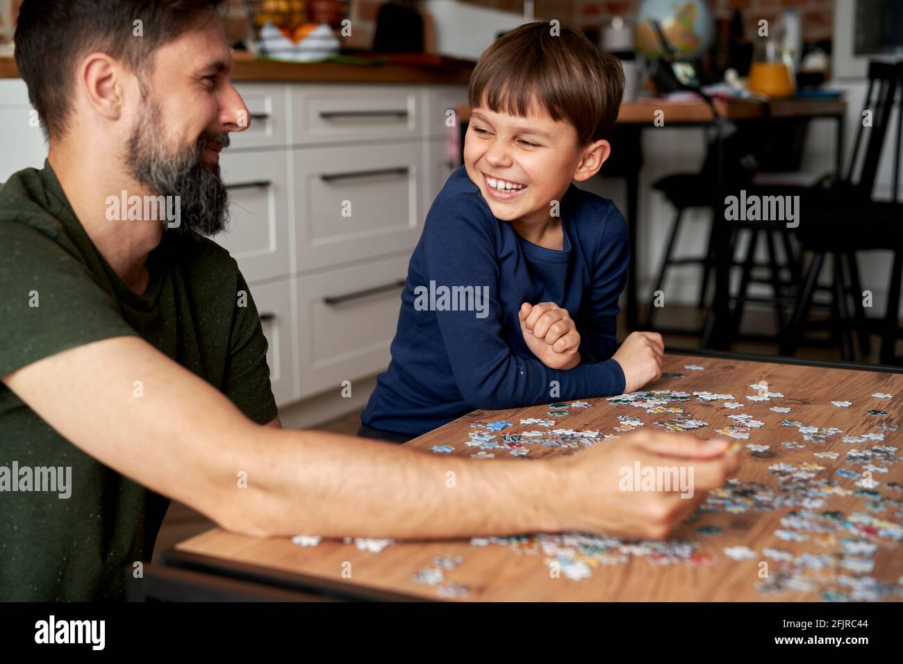 Glücklicher Sohn und Vater, der Spaß hat, während er das Puzzle vervollständigt Stockfoto