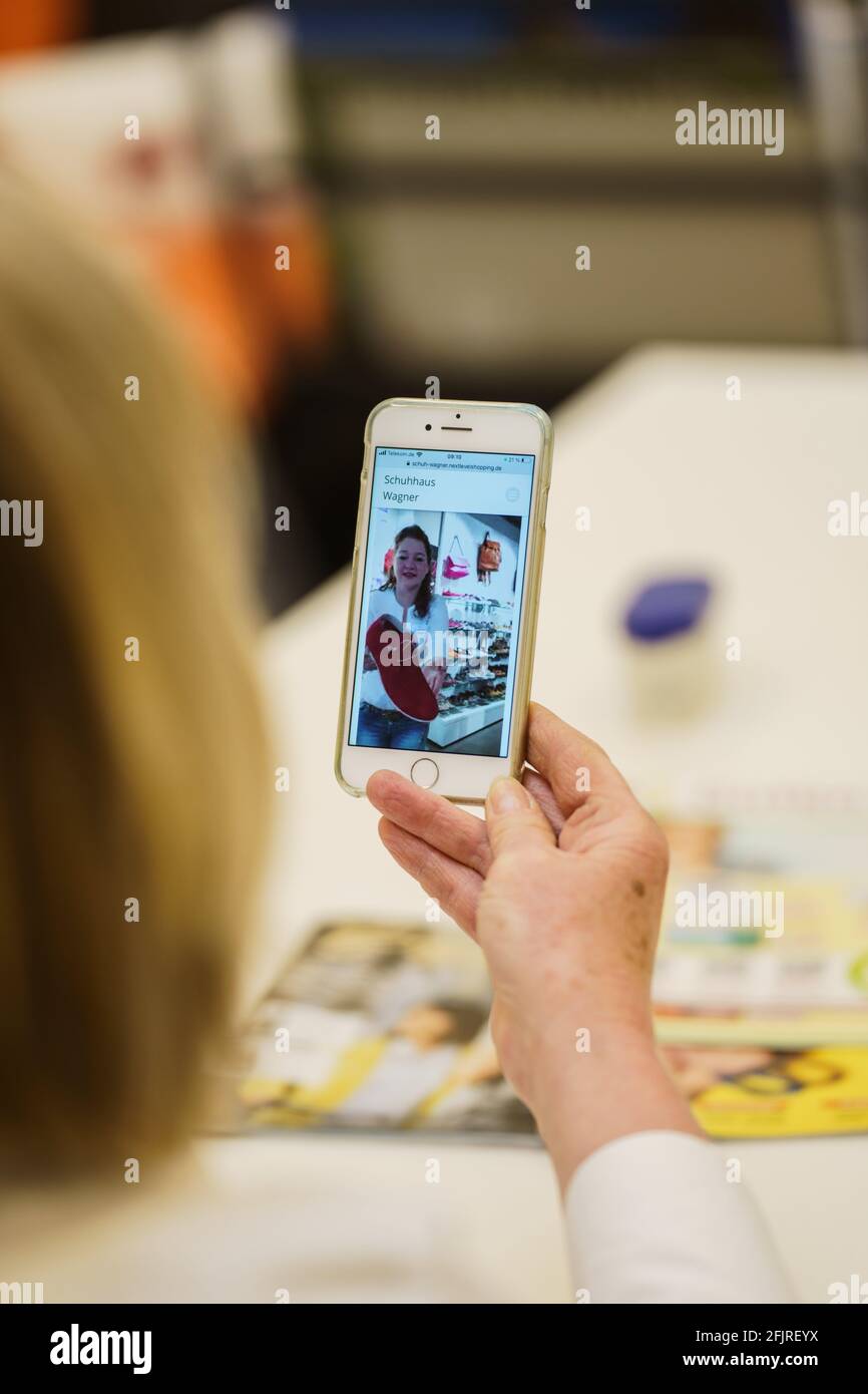 Bad Kreuznach, Deutschland. April 2021. Eine Kundin wird live von Claudia Holbach (zu sehen), Geschäftsführerin des „Schuhhaus Wagner“, beraten. Der Schuhladen „Schuhhaus Wagner“ bietet seinen Kunden Live-Video-Shopping. Kunden gehen live durch den Verkaufsraum mit fachkundiger Beratung über eine App und erhalten individuelle Beratung. (To dpa: 'Video-Shopping: Schuhe ausziehen, um zu Hause mit deinem Kleid auf dem Sofa zu gehen') Credit: Andreas Arnold/dpa/Alamy Live News Stockfoto