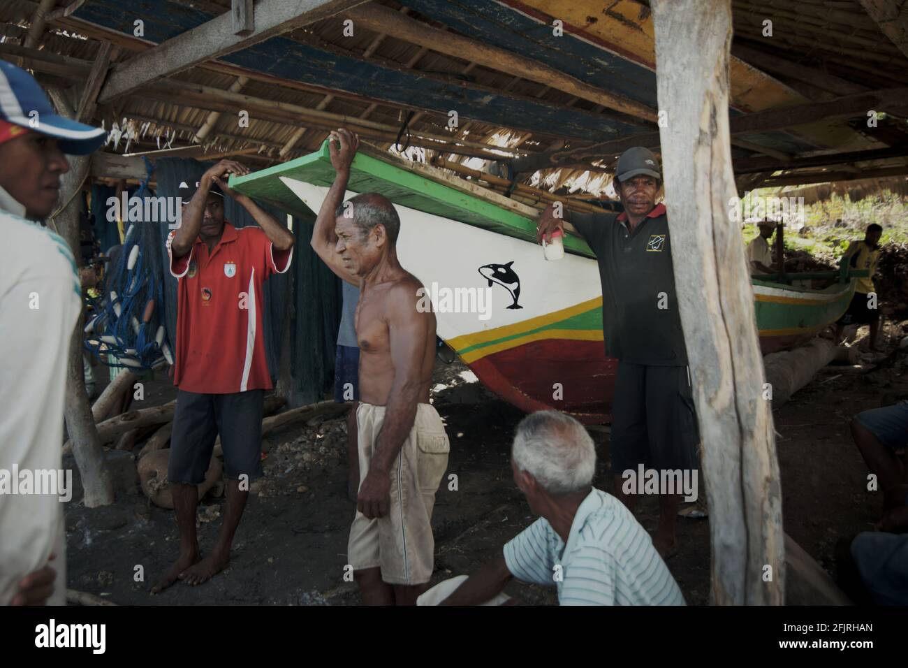 Eine Gruppe traditioneller Subsistenzfischer in einer Hütte, in der sie am Strand des Waldorfes Lamalera auf der Insel Lembata, Indonesien, ein Boot lagern. Stockfoto