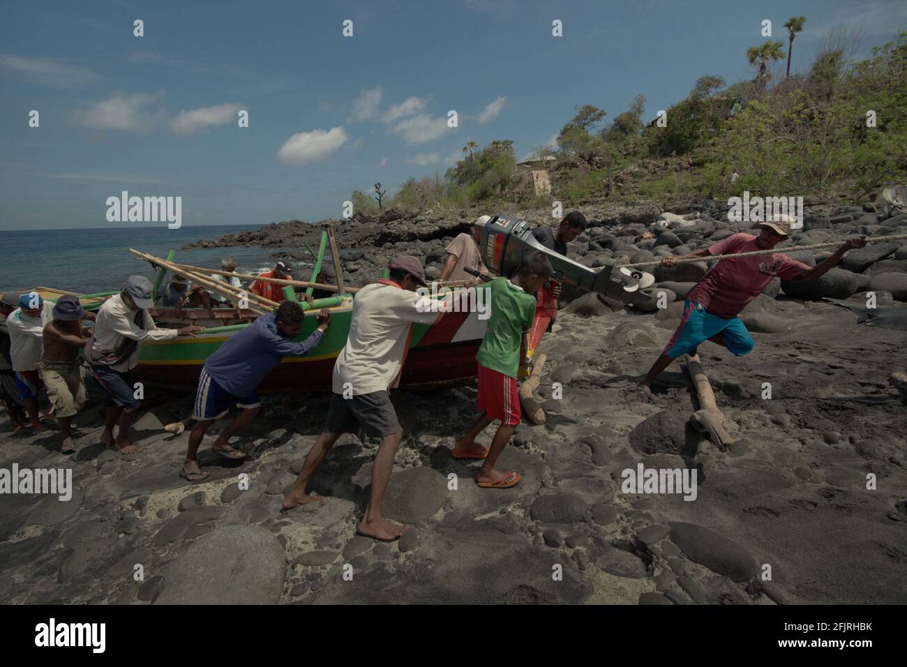 Menschen, die an einem felsigen Strand namens „Lamalera B“ im Walfangdorf Lamalera in Lembata, Ost-Nusa Tenggara, Indonesien, gemeinsam ein Boot fahren. Stockfoto