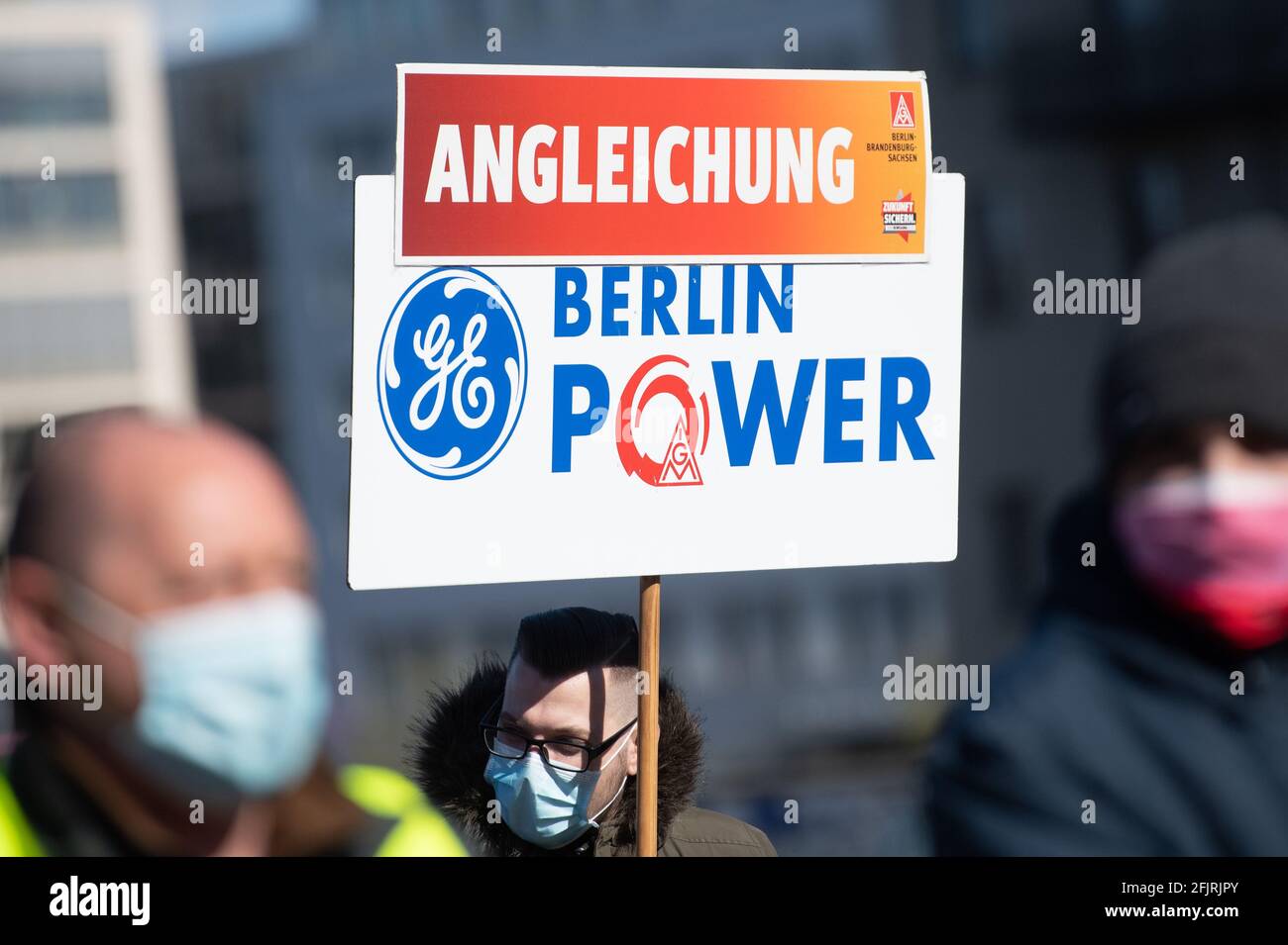 Berlin, Deutschland. April 2021. Auf der Oberbaumbrücke hält während einer Tarifverhandlungsveranstaltung der IG Metall zur Ausgleichung der Arbeitsbedingungen im Osten ein Stürmer ein Plakat mit der Aufschrift 'Angleichung - Berlin Power' hoch. 30 Jahre nach der Wiedervereinigung müssten Kollegen im Osten der Stadt und in Ostdeutschland unter anderem drei Stunden länger pro Woche arbeiten als im Westen. Quelle: Christophe Gateau/dpa/Alamy Live News Stockfoto