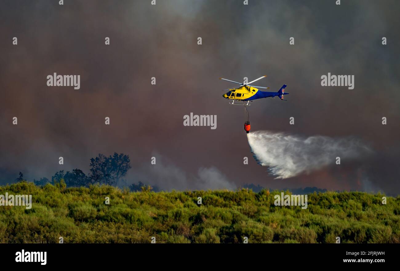 Hubschrauber mit bambi Eimer wirft Wasser mit Rauch in die Hintergrund Stockfoto