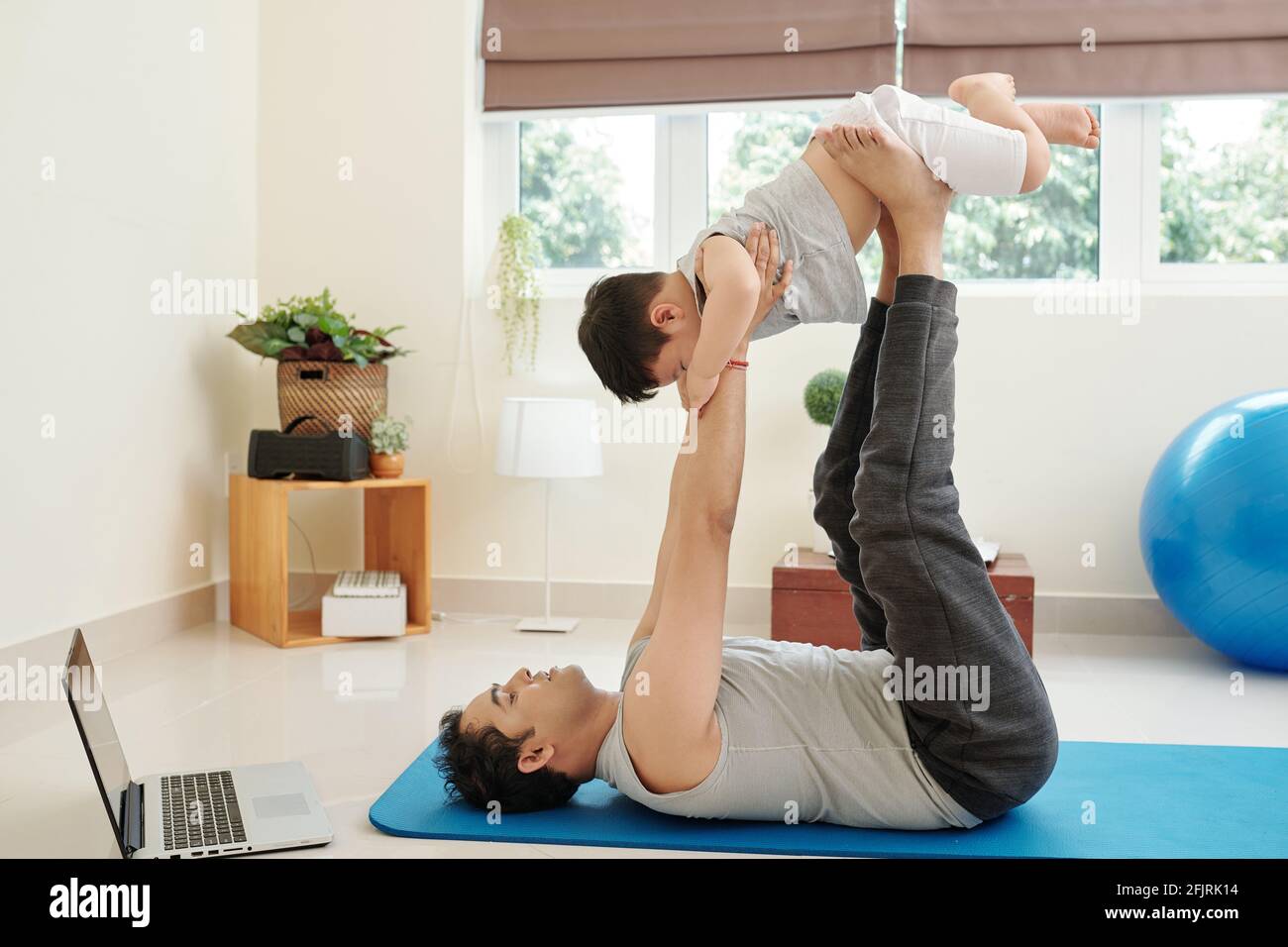 Glücklicher Vater hob seinen kleinen Sohn über den Kopf, wenn Zu Hause arbeiten Stockfoto
