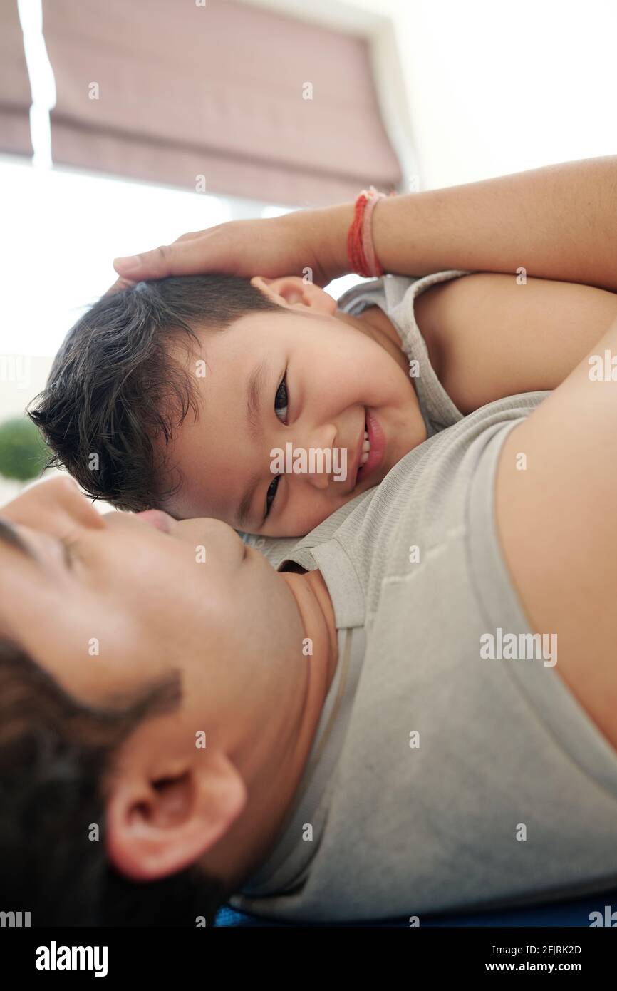Vater umarmte seinen lächelnden, glücklichen kleinen Sohn, als er sich darauf ausruhte Boden nach dem Training Stockfoto
