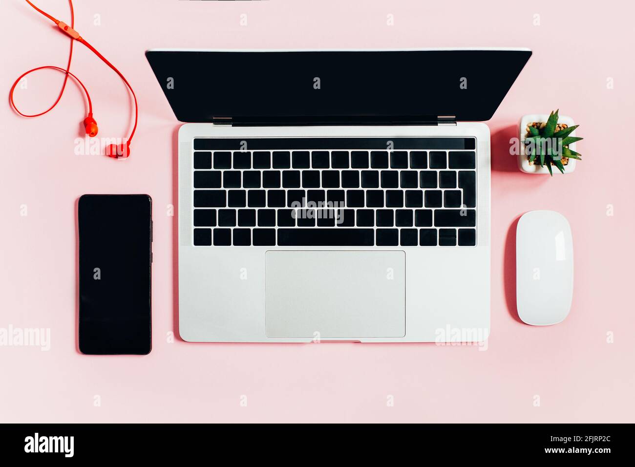 Draufsicht auf Laptop, Computermaus, Mobiltelefon, Kopfhörer auf rosa Hintergrund Stockfoto