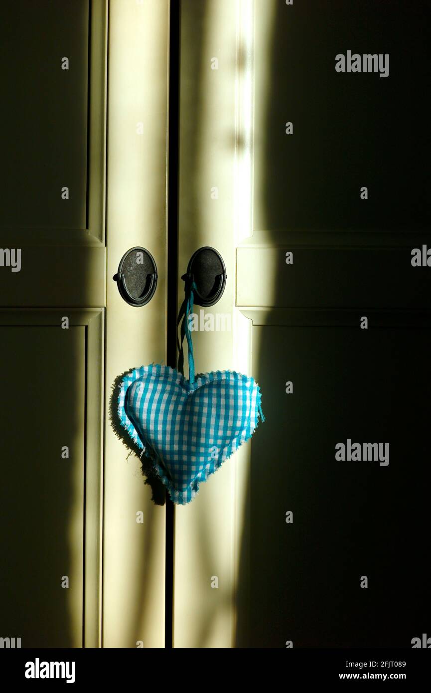 Gepolstertes blaues Herz, das an der Tür hängt Stockfoto