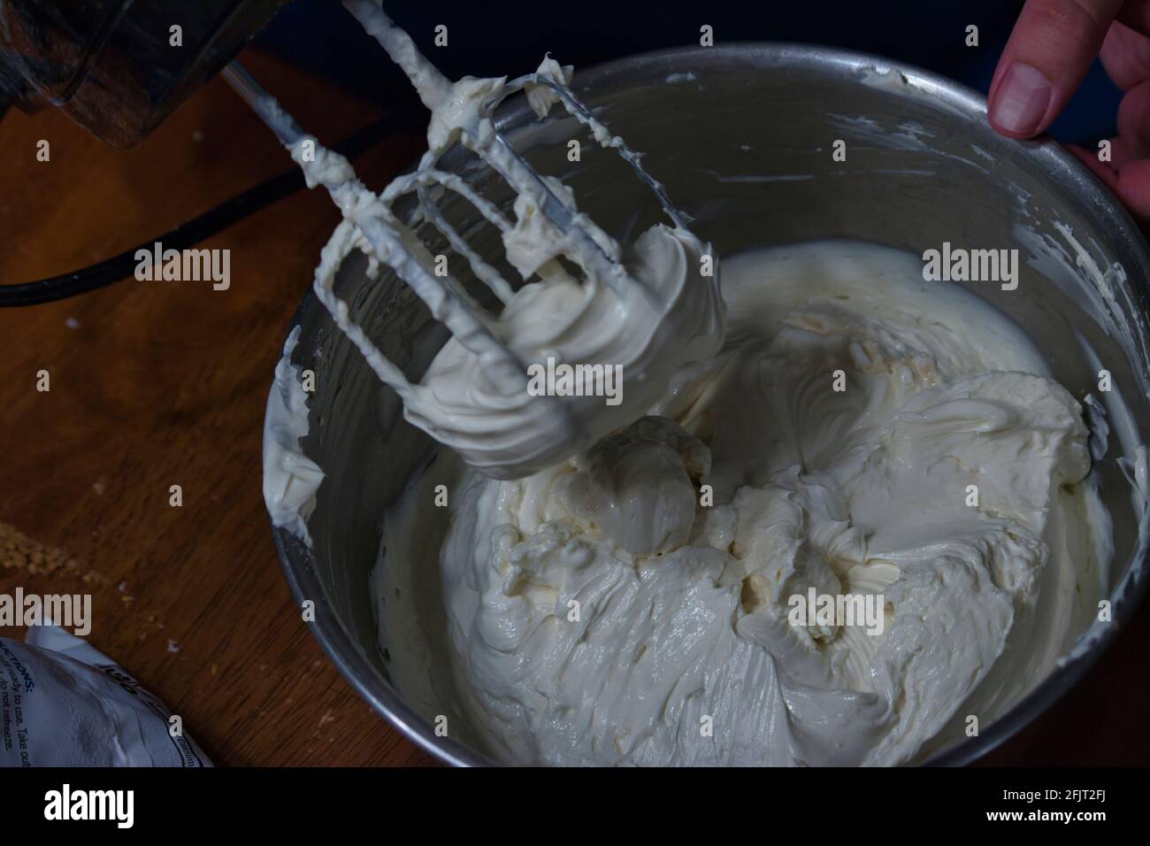 Ein elektrischer Mixer mit Schlagsahne, der die Quirle beschichtet Stockfoto
