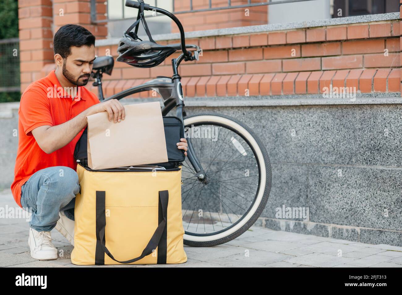 Kurier auf dem Fahrrad in Schutzhelm liefern Lebensmittel in der Stadt Und Online-Bestellung Stockfoto