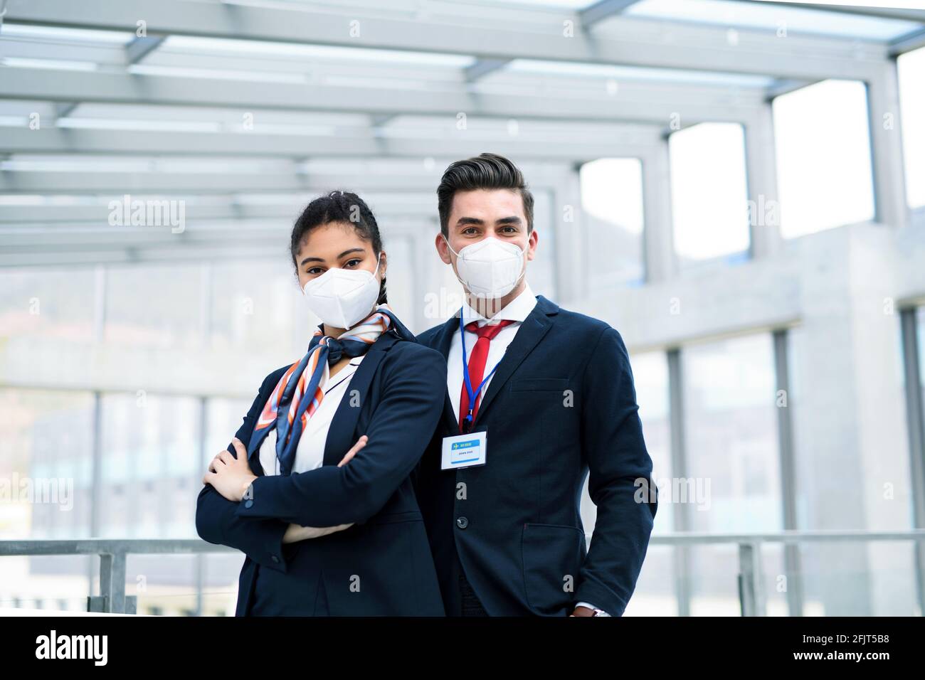 Junge Flugbegleiter, die in der Flughafenlounge auf die Kamera schauen, Coronavirus, Reisen und neue Normalität. Stockfoto